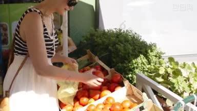 一名年轻女子在露天市场选购<strong>新鲜蔬菜</strong>，挑选成熟的红番茄